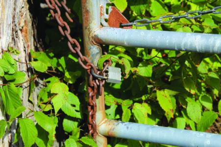 Closeup of a chain and padlock on a fence. The chain and gate show signs&hellip;